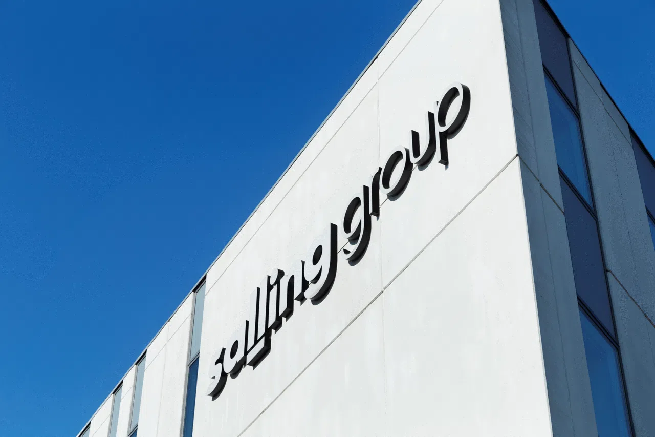 Close-up of the Salling Group logo on the side of a modern white building against a clear blue sky